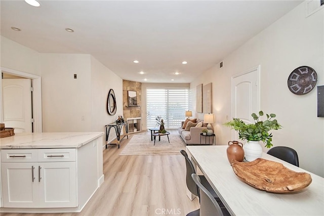 interior space featuring open floor plan, light stone countertops, light wood-type flooring, white cabinetry, and recessed lighting