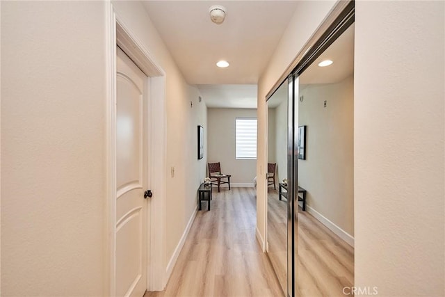 hallway with baseboards, recessed lighting, and light wood-style floors