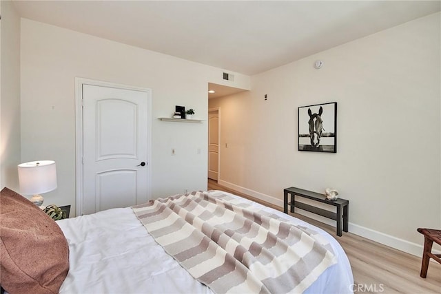 bedroom with light wood-style flooring, visible vents, and baseboards