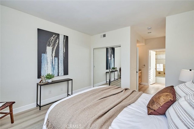 bedroom featuring connected bathroom, visible vents, baseboards, a closet, and light wood finished floors