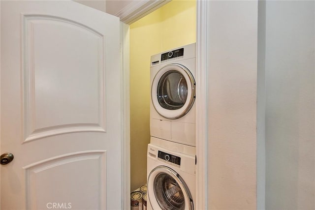 clothes washing area featuring stacked washer and clothes dryer and laundry area