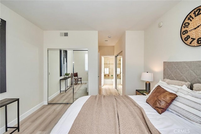 bedroom with a closet, visible vents, light wood-style floors, connected bathroom, and baseboards