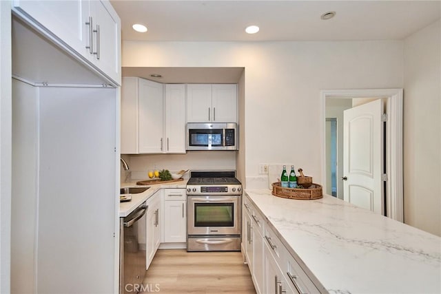 kitchen with appliances with stainless steel finishes, white cabinets, and a sink