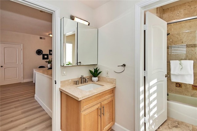 full bathroom featuring wood finished floors, visible vents, bathing tub / shower combination, vanity, and baseboards