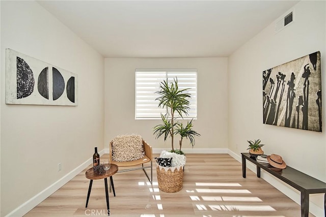 sitting room featuring light wood-style floors, visible vents, and baseboards