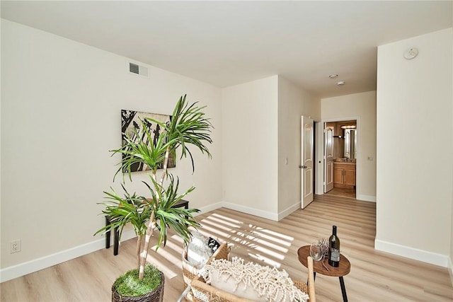 sitting room featuring light wood-style floors, visible vents, and baseboards