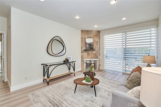 living room with recessed lighting, baseboards, light wood finished floors, and a tiled fireplace