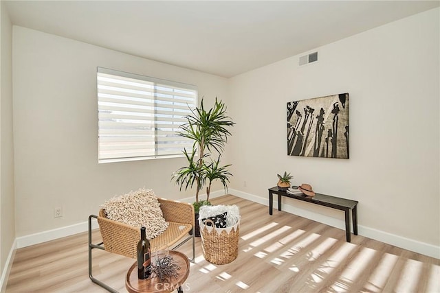 living area with light wood-type flooring, visible vents, and baseboards