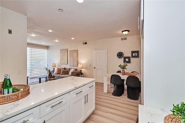 kitchen featuring white cabinets, light stone counters, open floor plan, light wood-style floors, and recessed lighting