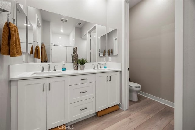 full bathroom featuring a sink, a shower stall, toilet, and wood finished floors