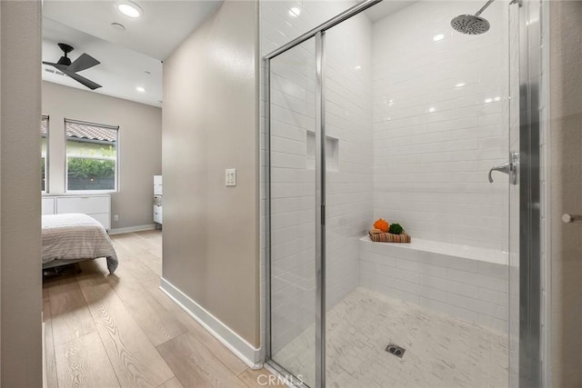 ensuite bathroom featuring baseboards, a ceiling fan, connected bathroom, wood finished floors, and a shower stall