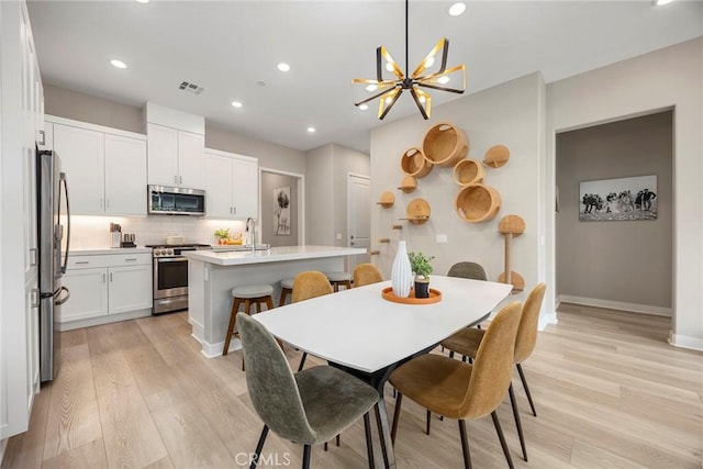 dining room featuring light wood-style flooring, visible vents, baseboards, and recessed lighting