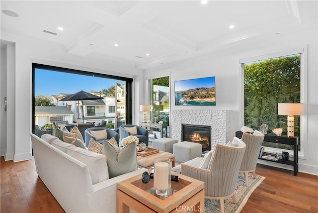 living area with a healthy amount of sunlight, coffered ceiling, a tiled fireplace, and wood finished floors