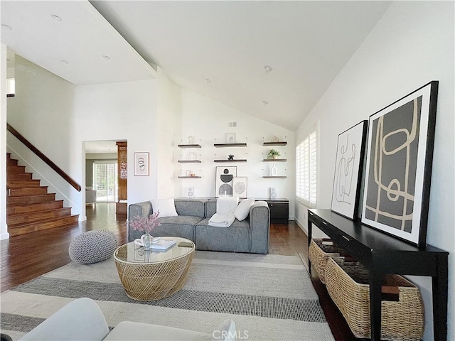 living room with high vaulted ceiling, stairway, and wood finished floors