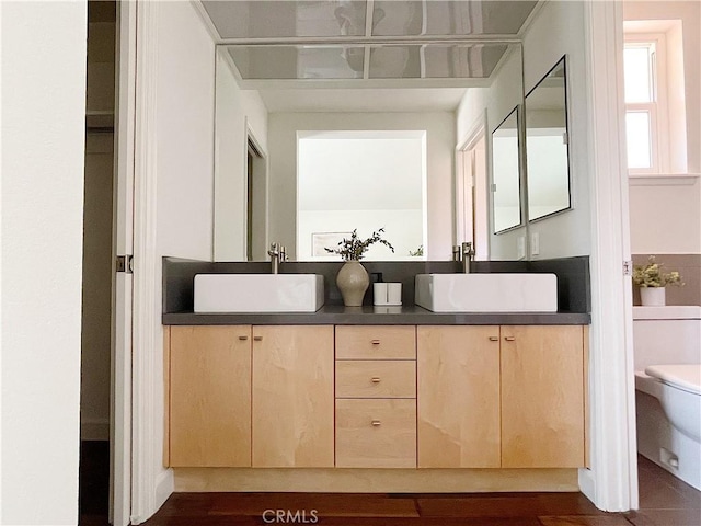 full bath with double vanity, a sink, and toilet