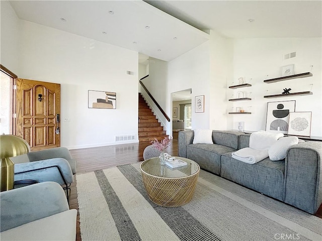 living area with stairway, visible vents, and high vaulted ceiling