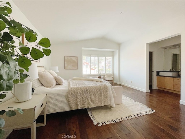 bedroom featuring vaulted ceiling, dark wood-style flooring, a sink, and baseboards