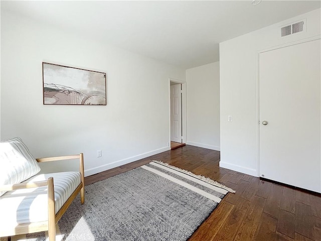 unfurnished room featuring dark wood-type flooring, visible vents, and baseboards