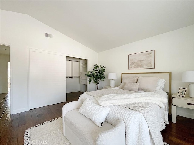 bedroom featuring a closet, dark wood-style flooring, visible vents, and vaulted ceiling