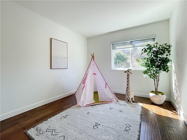 rec room featuring baseboards and dark wood-style flooring