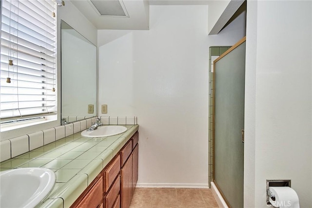 bathroom featuring double vanity, a stall shower, a sink, and tile patterned floors