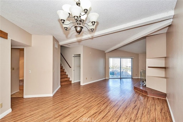 unfurnished living room with vaulted ceiling with beams, light wood finished floors, stairway, and a textured ceiling