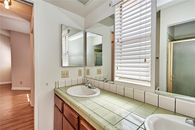 bathroom featuring an enclosed shower, wood finished floors, vanity, and baseboards