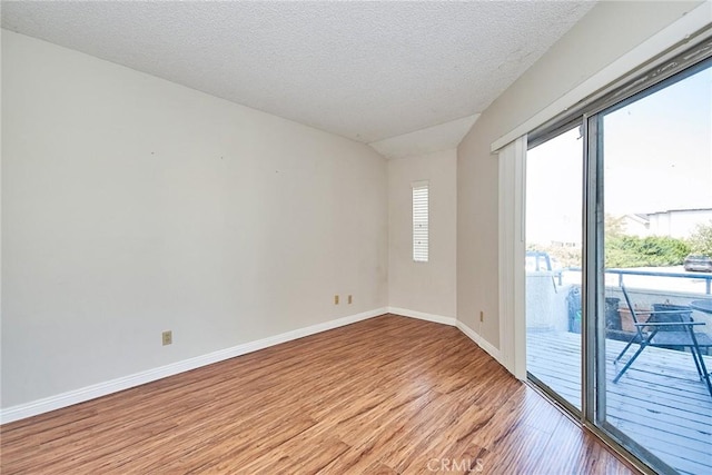 empty room featuring light wood-type flooring, a textured ceiling, and baseboards