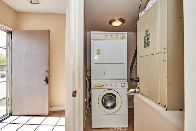 laundry room featuring laundry area, a textured ceiling, and stacked washer and clothes dryer