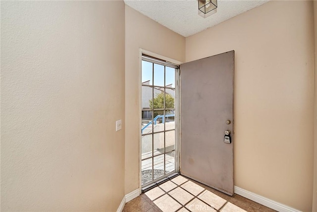 doorway featuring a textured ceiling and baseboards