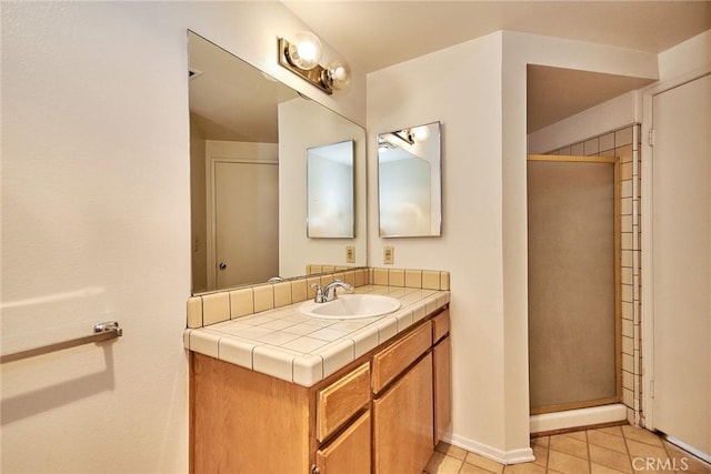 bathroom with tile patterned flooring, a shower stall, vanity, and baseboards