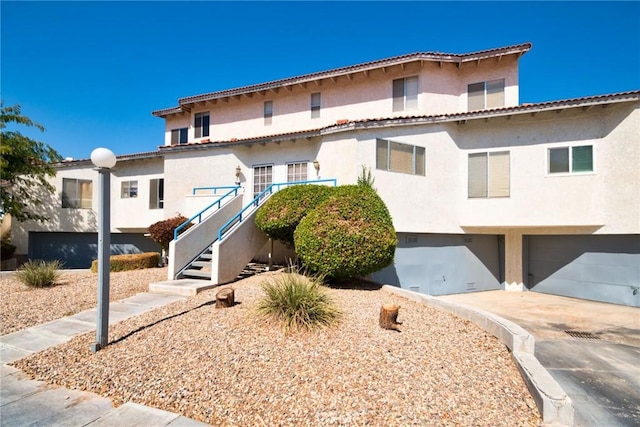 mediterranean / spanish-style home with driveway, an attached garage, stairway, and stucco siding