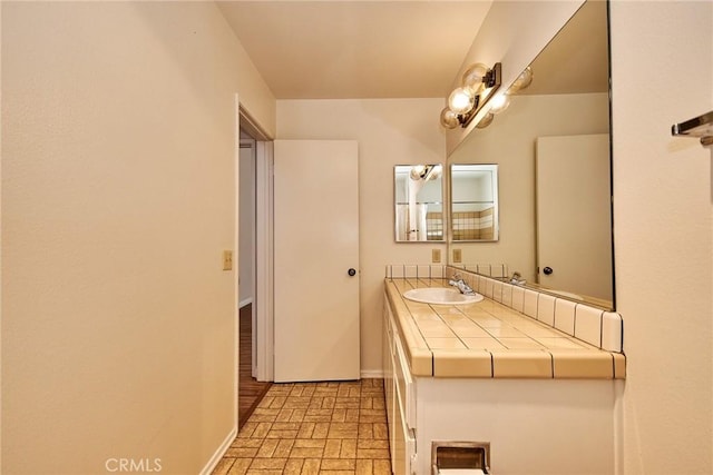 bathroom featuring brick floor, baseboards, and vanity