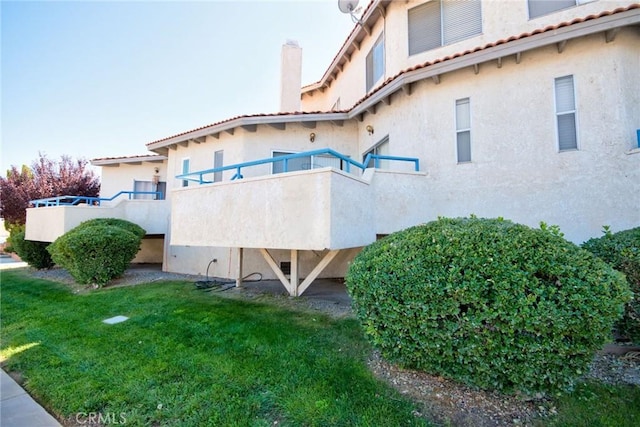 exterior space with a yard, a balcony, and stucco siding