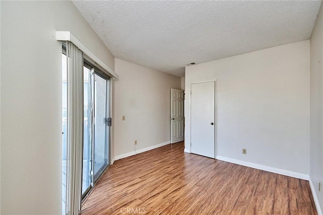 unfurnished room with baseboards, a textured ceiling, visible vents, and light wood-style floors