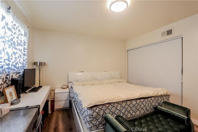 bedroom featuring dark wood-style floors, a closet, and visible vents