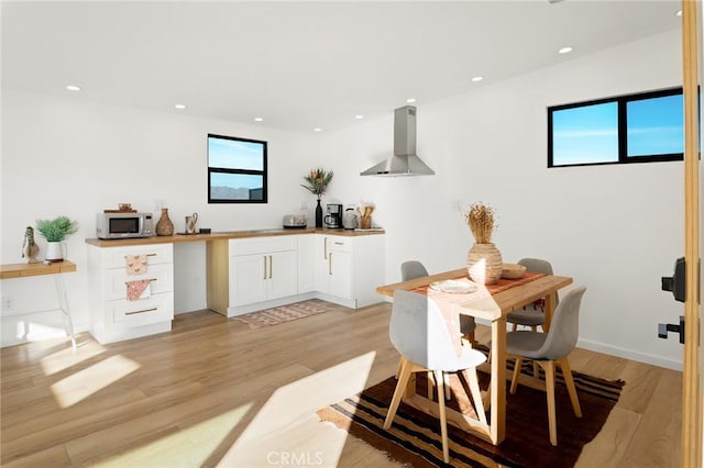 interior space featuring white cabinets, light wood-style floors, stainless steel microwave, and extractor fan