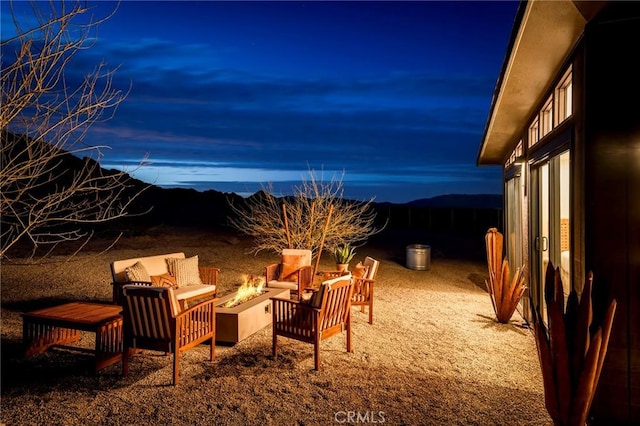 patio terrace at dusk with a mountain view and an outdoor living space with a fire pit