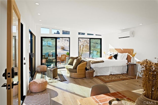 bedroom featuring a wall unit AC, light wood finished floors, access to outside, and recessed lighting