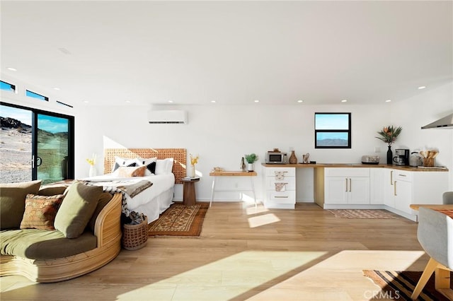 bedroom featuring light wood-type flooring, access to outside, recessed lighting, and a wall mounted AC