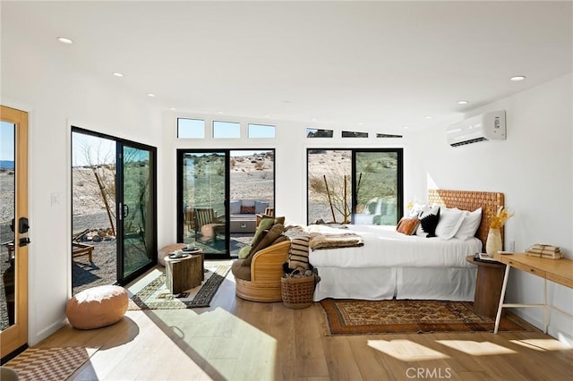 bedroom with light wood-type flooring, access to exterior, multiple windows, and a wall mounted AC