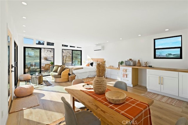 living room featuring a wall unit AC, light wood-style flooring, and recessed lighting