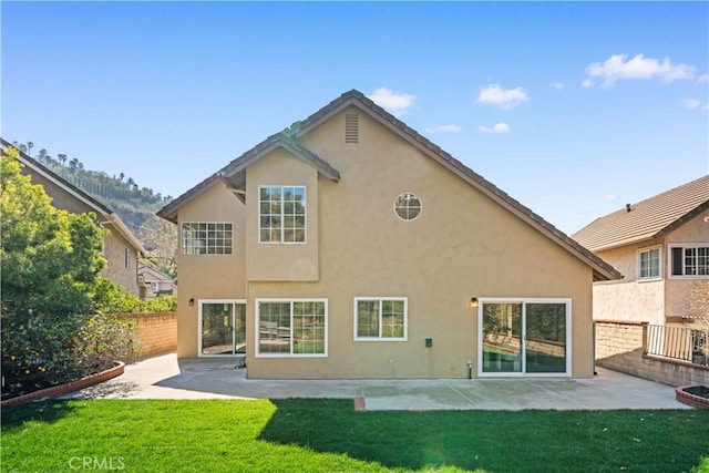 rear view of house with a yard, a patio area, fence, and stucco siding