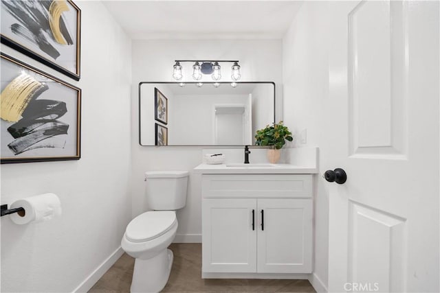 bathroom with baseboards, vanity, and toilet