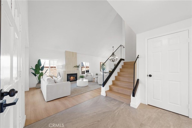 foyer with stairs, high vaulted ceiling, a fireplace, and wood finished floors