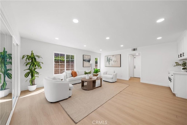 living area with baseboards, light wood finished floors, visible vents, and recessed lighting