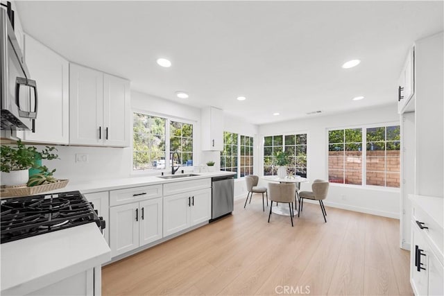 kitchen featuring light wood-style flooring, stainless steel appliances, a sink, and light countertops