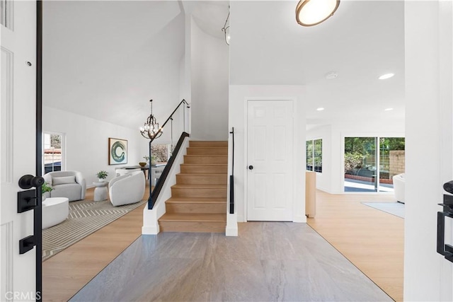 entryway featuring wood finished floors, a notable chandelier, plenty of natural light, and stairs