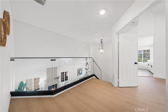 interior space featuring wood finished floors, a glass covered fireplace, visible vents, and recessed lighting