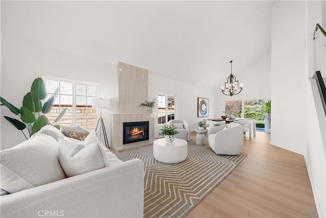 living area with high vaulted ceiling, a wealth of natural light, and a large fireplace